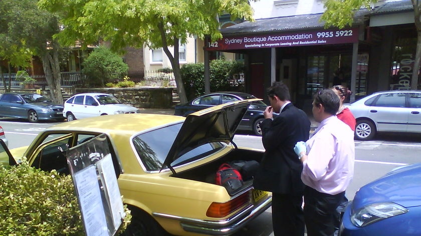 Detectives search a car after arresting two men at a McMahon's Point cafe.