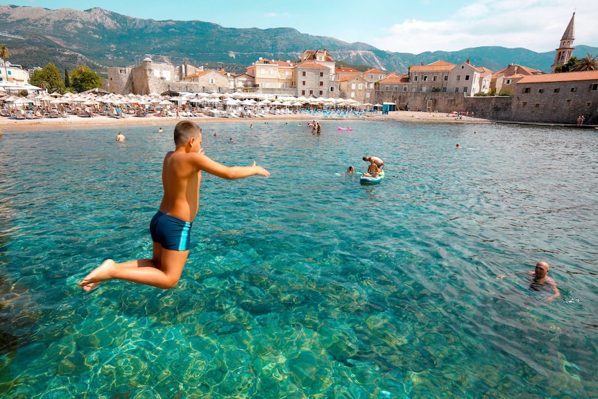 A boy jumps into the water in a bay in Montenegro