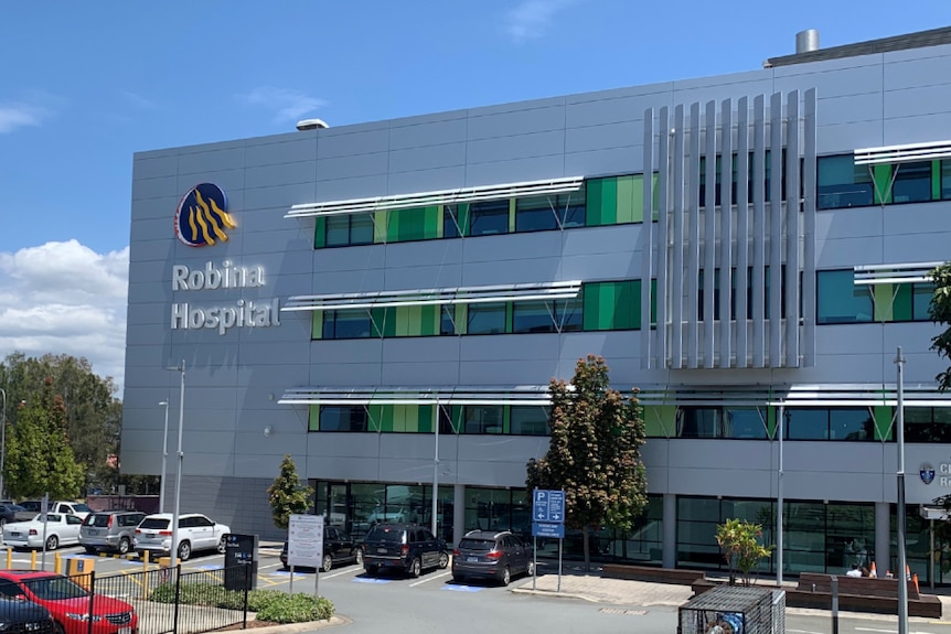 A four-story building with the words 'Robina Hospital' and adjacent carpark