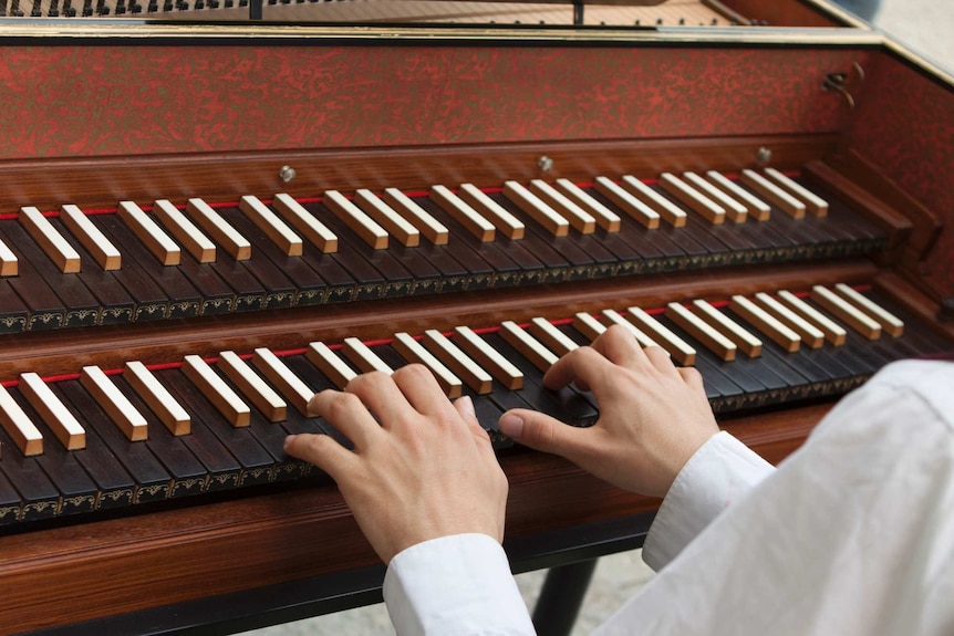 Close-up of hands playing a harpsichord.