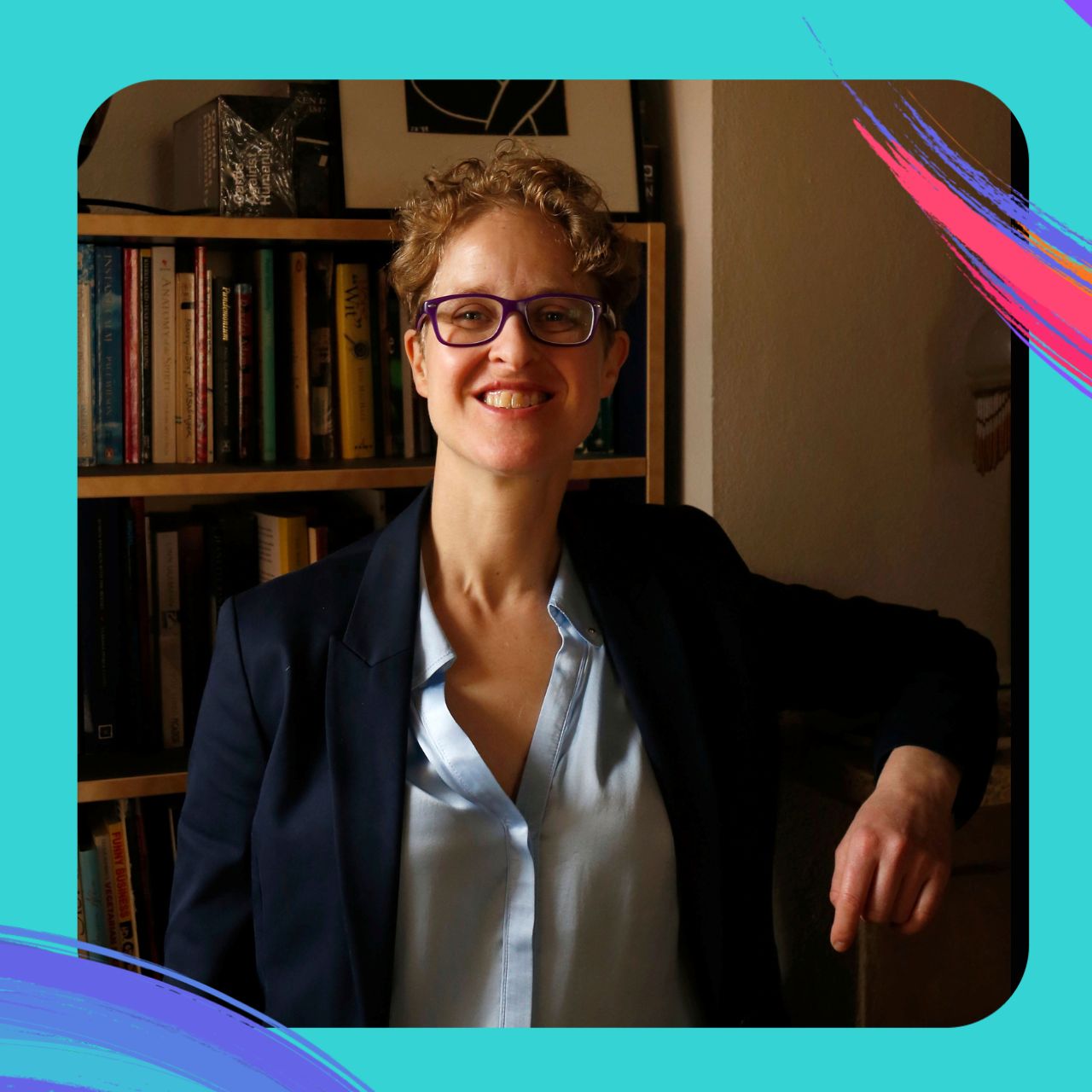 Sharonne Zaks smiles, standing in front of a full bookshelf.