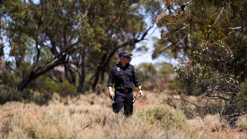 A police officer walks through scrub