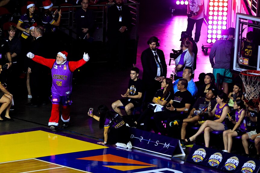 Santa Claus dressed in a basketball jersey walks out onto the court