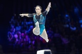 Gymnast Georgia Godwin jumps in the air, legs apart, during a beam routine
