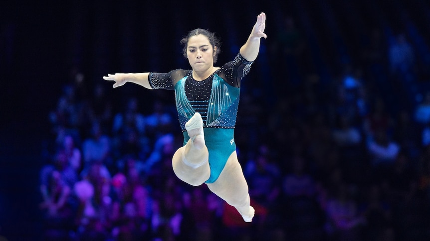 Gymnast Georgia Godwin jumps in the air, legs apart, during a beam routine