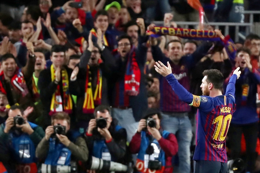 Messi stands with arms raised in front of fans after scoring a goal in a Champions League semi-final.