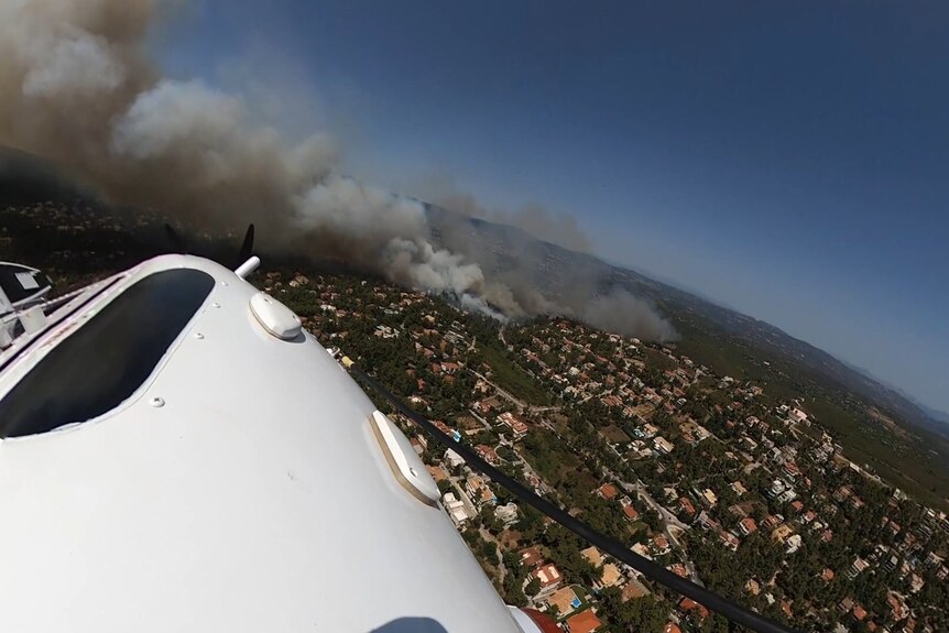 Smoke, seen from an aeroplane, billows over a densely populated suburb.