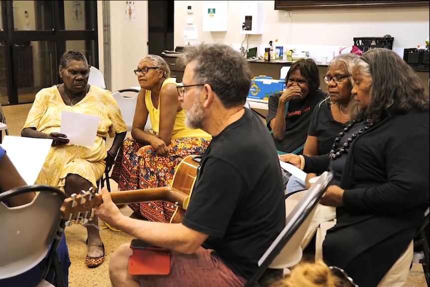 A group singing with a guitarist.