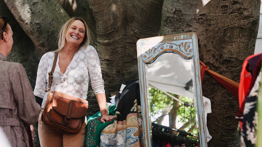 A woman stands beside a tree