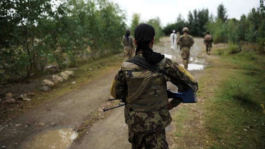 Afghan National Army soldier walks behind US soldiers