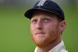 Ben Stokes, wearing his England whites and cap, looks up to the sky