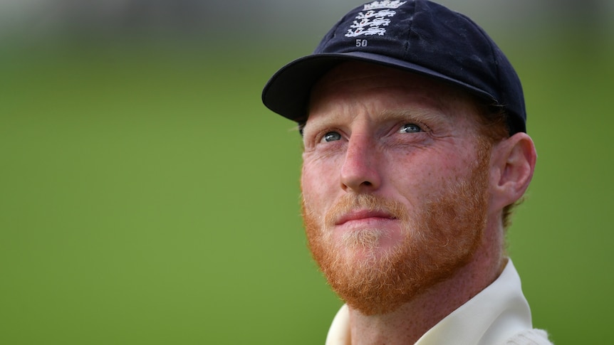 Ben Stokes, wearing his England whites and cap, looks up to the sky
