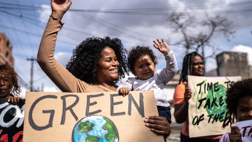 A demonstration for action on Climate Change showing young woman and child holding a placard of the earth.