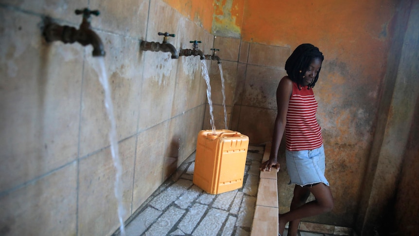 A female resident in Port-au-Prince, Haiti, fills a container with water.