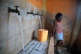 A female resident in Port-au-Prince, Haiti, fills a container with water.