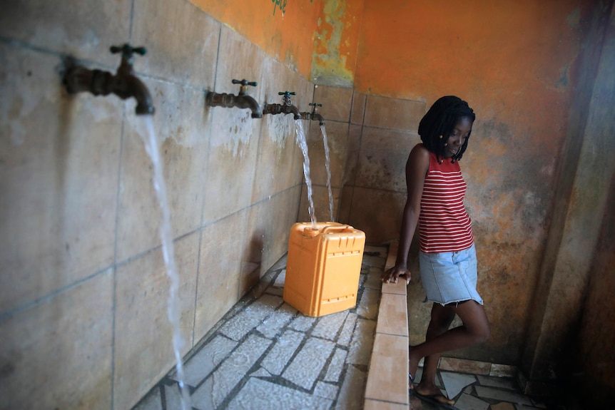 A resident in Port-au-Prince, Haiti, fills a container with water.