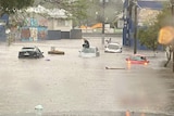 Cars stuck in floodwater, a man sitting on the roof of a car