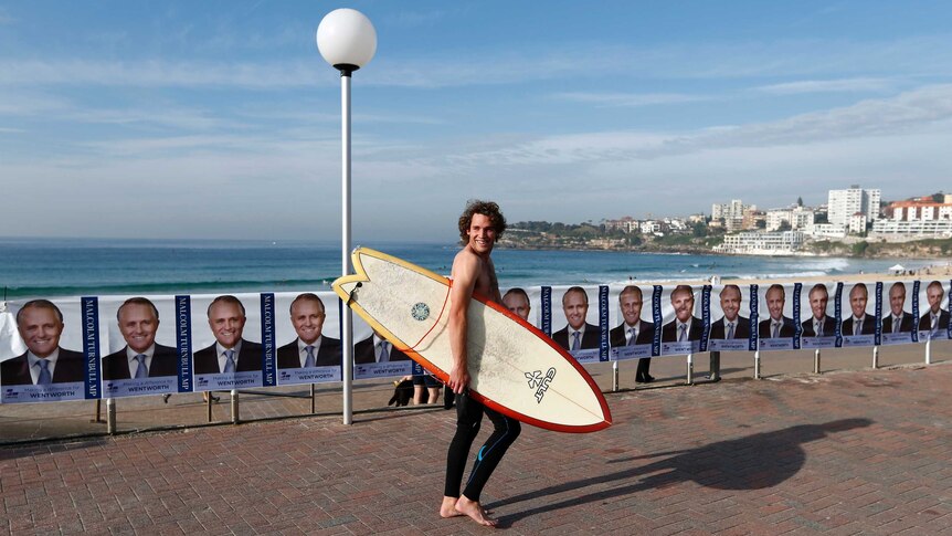 A surfer walks past posters of Malcolm Turnbull on the morning of the federal election.