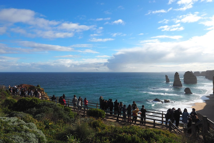 Tourists line up along the boardwalk to see the 12 Apostles, large rock columns in the ocean.
