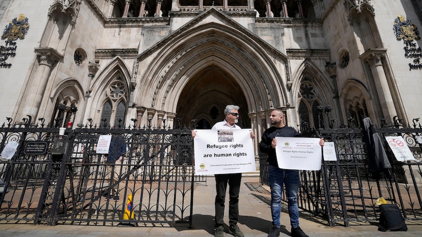 Two men with signs stand outside court building.