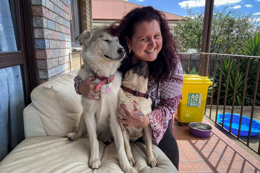 A woman smiles while posing for a photo with two dogs