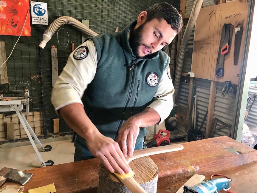 A ranger sanding a boomerang.