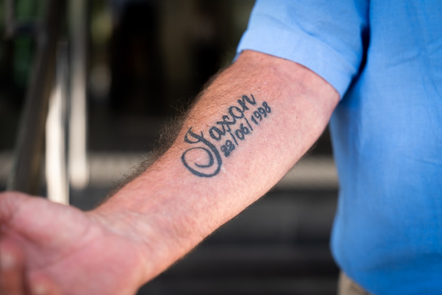 A tattoo on a man's arm that reads 'Jaxon, 28/06/1998