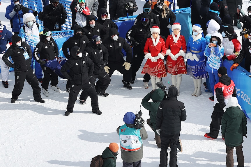 A group of people in black winter clothes perform a dance