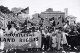 Black and white photo of protestors holding Aboriginal flags