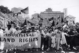 Black and white photo of protestors holding Aboriginal flags