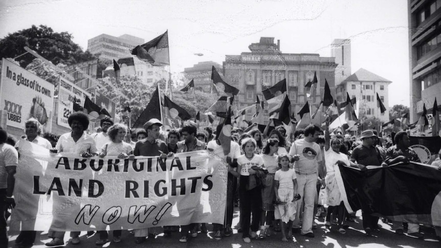 Black and white photo of protestors holding Aboriginal flags