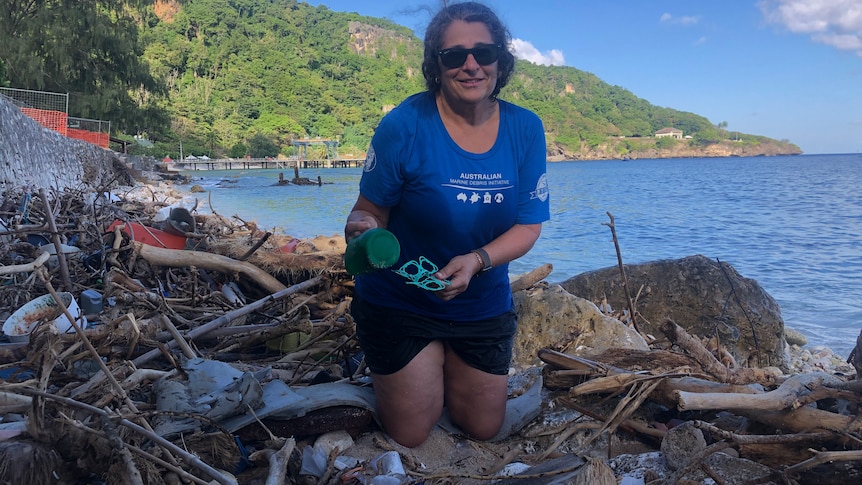 Woman holding marine debris on the beach of Christmas Island.
