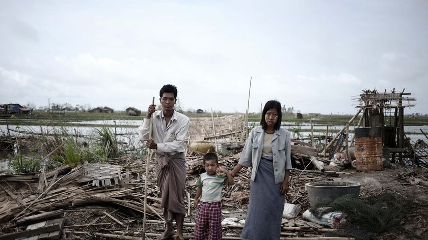 A family stands on the debris of their house, near Rangoon, destroyed by the cyclone.