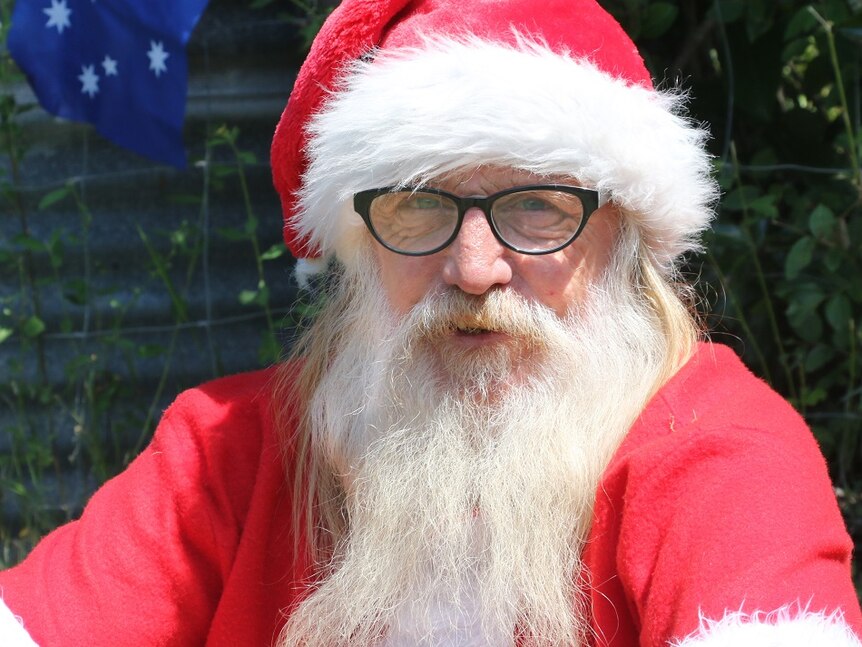 Man with long white beard dressed up in Santa suit