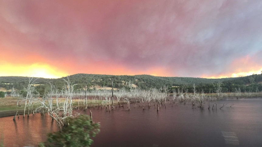 A bright yellow and red glow from a big bushfire rises above hills beyond Harvey dam.