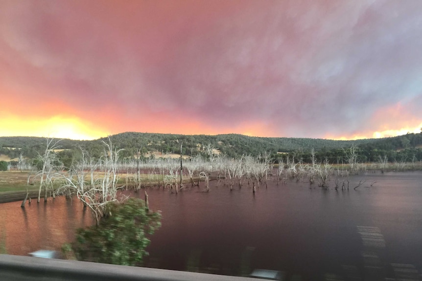 A bright yellow and red glow from a big bushfire rises above hills beyond Harvey dam.