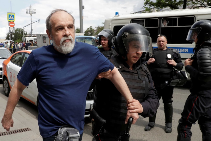 Russian policeman holds arm of anti-corruption protester in Moscow