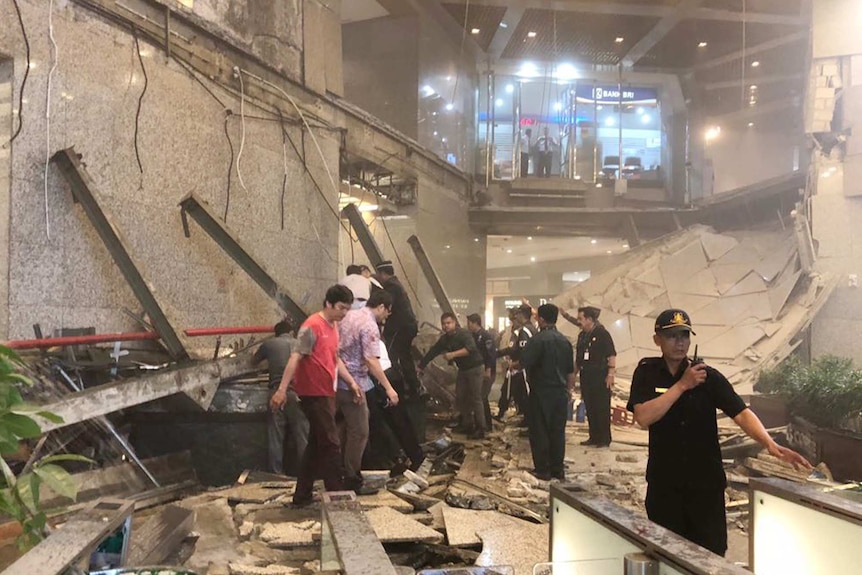 Security stands guard in front of a collapsed floor.
