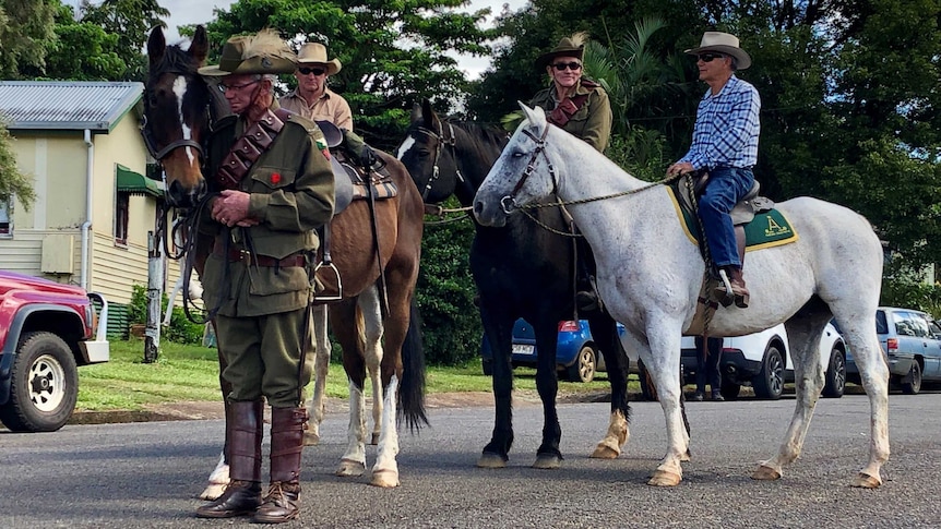 Horses and their riders, some dressed in World War 2 uniforms, wait to lead a funeral procession