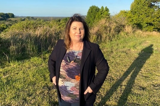 A woman stands on empty land with her hands on her hips