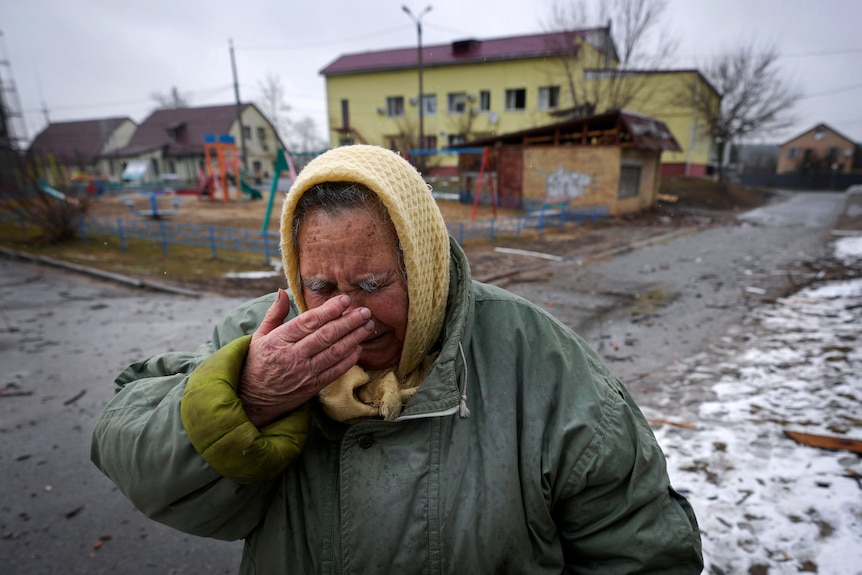 A woman cries outside houses damaged by a Russian airstrike.