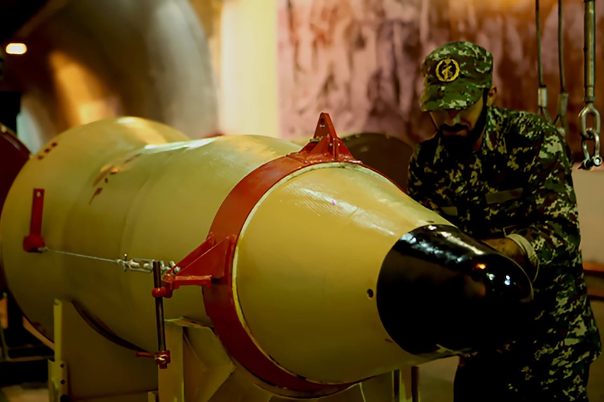 An Iranian Revolutionary Guard stands next to a missile launcher