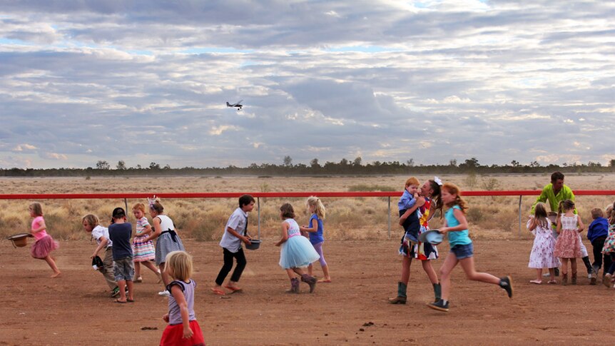 The kids collect lollies off the race track while the mustering plane circles overhead.