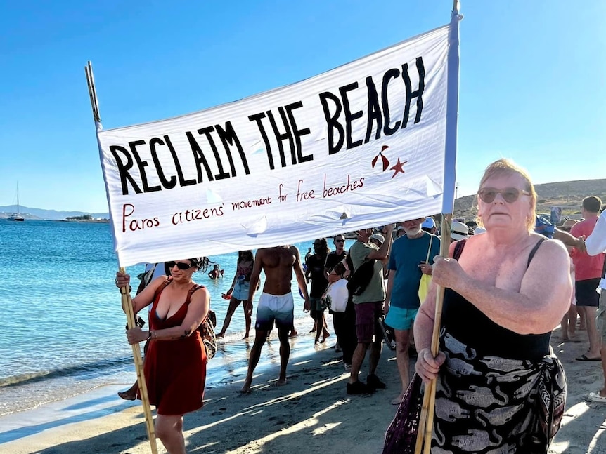 해변에서 팻말을 들고 있는 두 여성 "해변 복원"