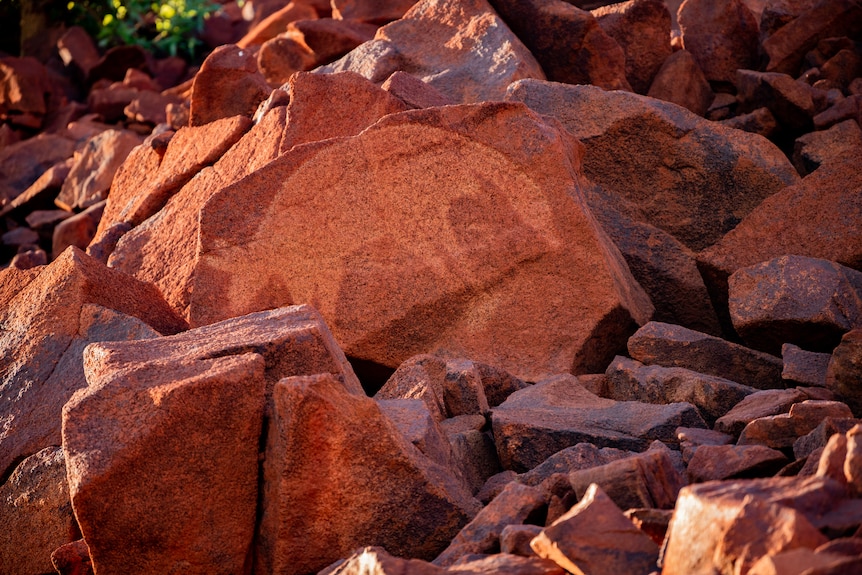 A petroglyph in Murujuga, Western Australia, shows a kangaroo, on red rock.