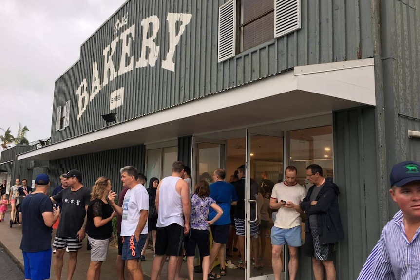 Holidaymakers on Hamilton Island line up outside the Bakery after Cyclone Debbie.