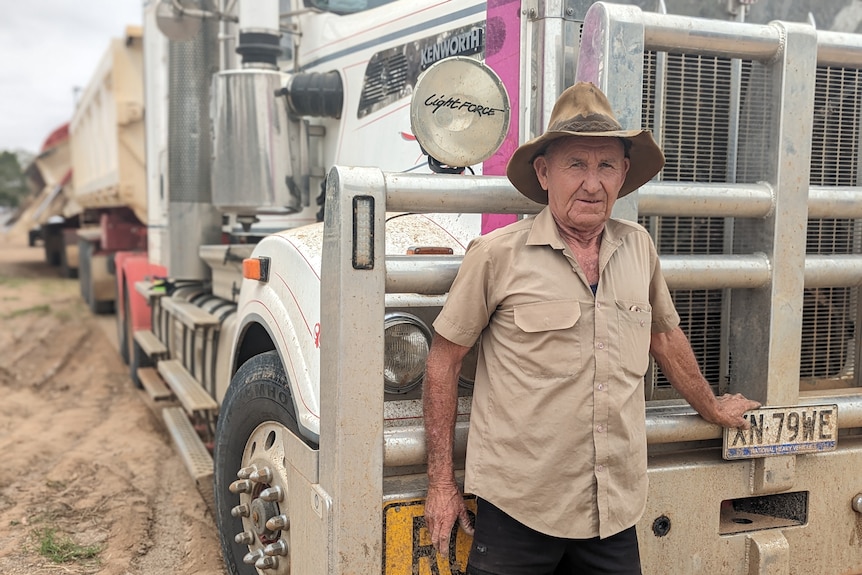 An older white man, Stephen Clarke, wears a tattered akubra and stands in front of his truck.