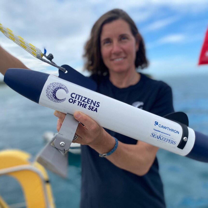 A researcher holding a device used to capture data from ocean water as its towed behind a boat