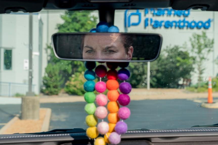 A woman's eyes in a car rearview mirror.