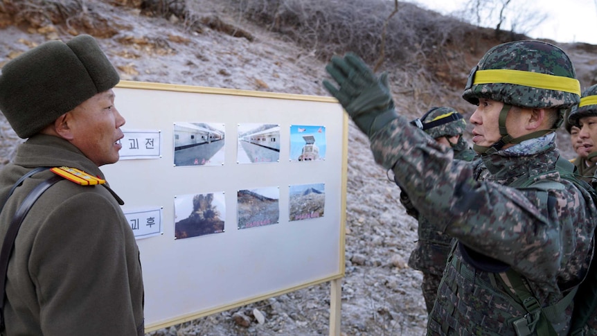 A South Korean soldier speaks and gestures to a North Korean soldier at the DMZ.